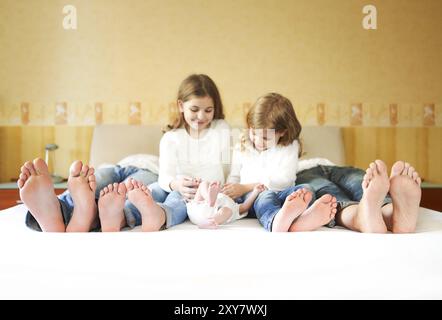 Süße Familie im Bett. Vater, Mutter und drei kleinen Kindern, in der Nähe auf den Füßen Stockfoto