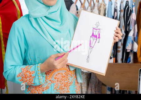 Der Besitzer eines kleinen Schneidergeschäfts stellt Kleidungsstücke vor Stockfoto