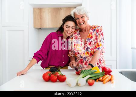 Wunderschöne Großmutter und Enkelin kochen zu Hause zusammen - fröhliche Oma und Neffe verbringen gute Zeit miteinander Stockfoto