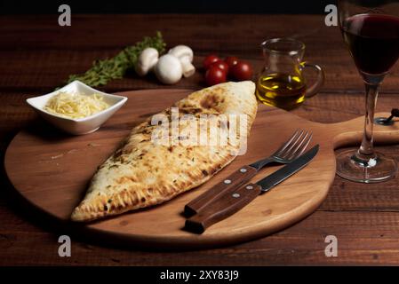 Calzone, traditionelle italienische Zubereitung, begleitet von Gewürzen und Rotwein Stockfoto