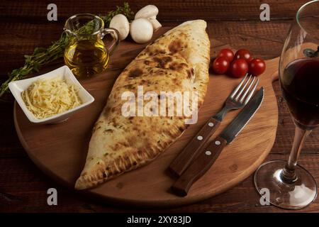 Calzone, traditionelle italienische Zubereitung, begleitet von Gewürzen und Rotwein Stockfoto