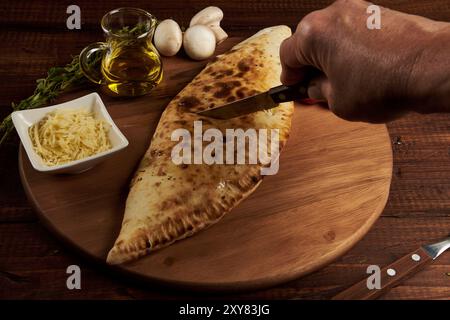 Calzone, traditionelle italienische Zubereitung, begleitet von Gewürzen und Rotwein Stockfoto