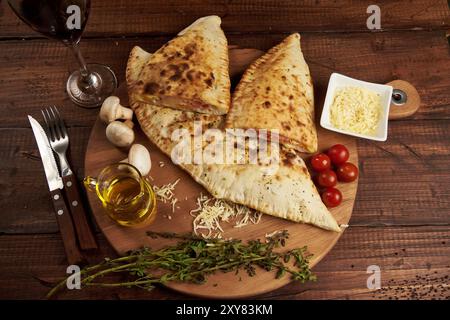 Calzone, traditionelle italienische Zubereitung, begleitet von Gewürzen und Rotwein Stockfoto