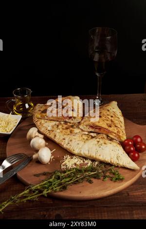 Calzone, traditionelle italienische Zubereitung, begleitet von Gewürzen und Rotwein Stockfoto