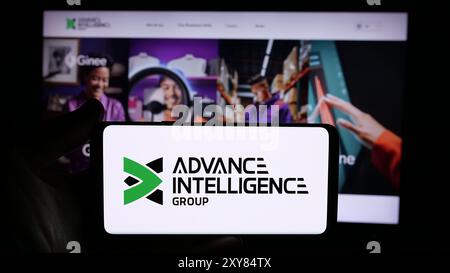 Person, die ein Handy mit dem Logo des singapurischen Fintech-Unternehmens Advance Intelligence Group vor der Webseite hält. Schwerpunkt auf dem Display des Telefons. Stockfoto