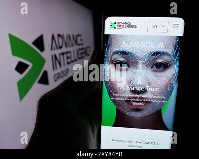 Person, die ein Handy hält, mit Website der singapurischen Fintech-Firma Advance Intelligence Group mit Logo. Konzentrieren Sie sich auf die Mitte des Telefondisplays. Stockfoto