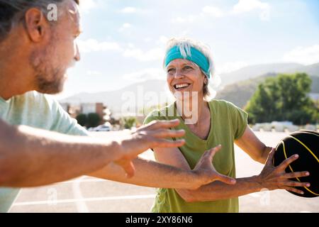 Wunderschönes glückliches Seniorenpaar, das Basketball spielt und Spaß hat - reifes verheiratetes Paar, das verliebt ist, sich im Freien zu verbinden und gemeinsam Sport zu treiben, Konzepte ab Stockfoto