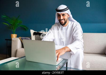 Arabischer Mann in traditioneller emiratischer Kleidung, der im Büro arbeitet - Porträt eines Geschäftsmannes aus dem Nahen Osten Stockfoto