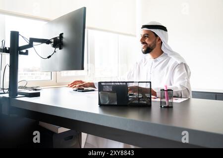 Arabischer Mann in traditioneller emiratischer Kleidung, der im Büro arbeitet - Porträt eines Geschäftsmannes aus dem Nahen Osten Stockfoto