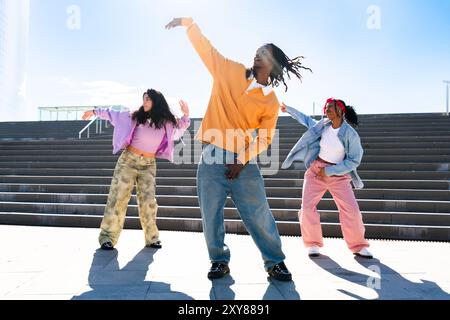 Junge Gruppe multiethnischer Hip-Hop-Tänzer in farbenfrohen urbanen Streetwear-Tänzen - stilvolles multirassisches Rap-Crew-Porträt in der Stadt Stockfoto