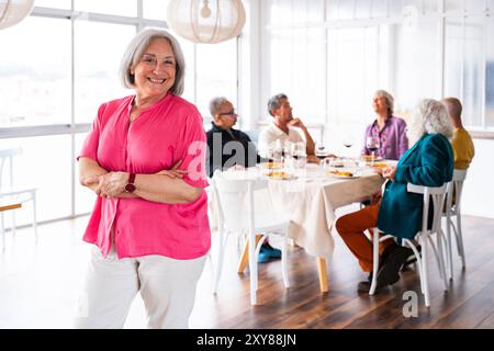 Eine Gruppe glücklicher Seniorenfreunde, die sich zu Hause für eine Dinnerparty zusammenschließen - fröhliche und Jugendliche alte, reife, multiethnische Leute, die Spaß haben Stockfoto