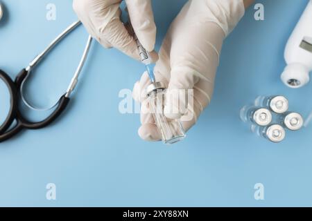 Medizin Behandlung, Impfkonzept. Arzt Hände halten Flasche mit Impfstoff und Injektionsspritze, elektronisches Thermometer, Stethoskop und vac Stockfoto