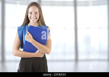 Junge Frau mit Notebooks auf dem Arm, in einer Schule Stockfoto