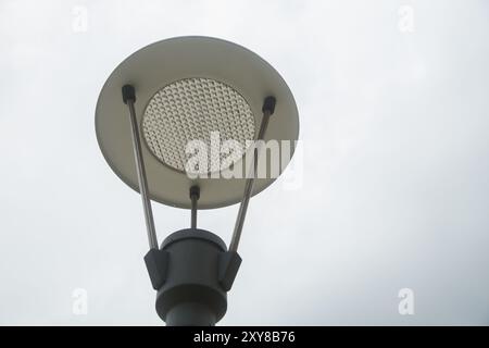 Moderner Lichtmast. Eine vertikale Aufnahme einer metallischen Straßenlaterne gegen den bewölkten blauen Himmel. led-Laterne auf blauem Himmel Hintergrund, Seitenansicht Stockfoto