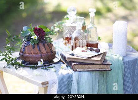 Cocolate Kuchen verziert mit Blumen und drei Whiskey Dekanter gegen einen hellgrauen Hintergrund mit Textfreiraum Stockfoto