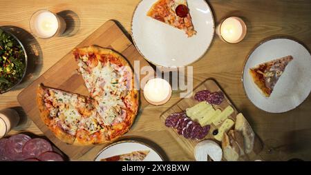 Tabelle mit verschiedenen Lebensmitteln mit Rotwein und Kerzen serviert. Stockfoto