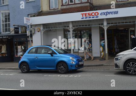 Ein Blue Fiat 500 parkte vor Tesco Express an der High Street. Cowbridge, Vale of Glamorgan, Wales, Vereinigtes Königreich. Juni 2024. Stockfoto