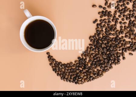 Beige flach Lay Hintergrund mit weißer Keramik Tasse Kaffee, geröstete Kaffeebohnen Dampf Form von heißem Kaffee. Idee und Zusammensetzung mit Kaffeebohnen s Stockfoto