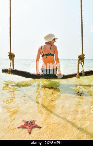 Weibliche Touristen auf Schaukeln genießen Seestern Strand auf der berühmten tropischen Insel Koh Rong, Kambodscha. Touristische Sehenswürdigkeiten berühmte südostasien Insel Schwimmen Pose Stockfoto