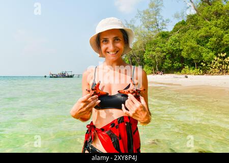 Weibliche Touristen halten rote Seesterne am Sternfischstrand auf der berühmten tropischen Insel Koh Rong, Kambodscha. Touristische Besichtigungstour berühmte südostasien-isla Stockfoto