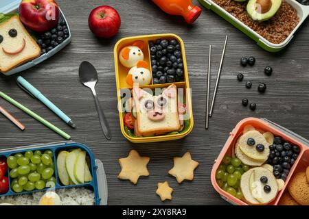 Lunchboxen mit verschiedenen Snacks, eine Flasche Saft und Besteck auf Holztisch, flache Ladefläche Stockfoto