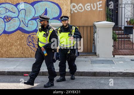 London, Großbritannien. August 2024. Zwei Polizisten werden während des Karnevals in Notting Hill abgebildet. Mehr als eine Million Nachtschwärmer nehmen am Notting Hill Carnival Teil, einem fest der karibischen Kultur, das als Europas größtes Straßenevent gilt. Quelle: Mark Kerrison/Alamy Live News Stockfoto