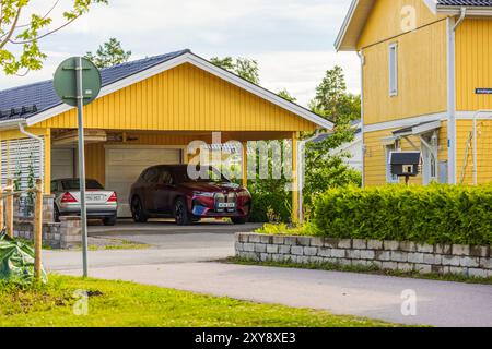 Nahaufnahme der Villa mit gelb lackiertem Holzhaus und Garage mit BMW iX40 Elektroauto und Mercedes in der Garage. Stockfoto