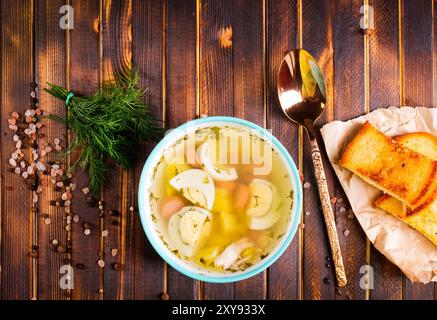 Eiersuppe mit Fleisch in einer Schüssel aus weißem Porzellan auf Holztisch. Stockfoto