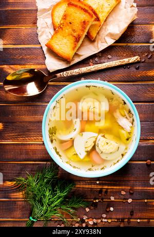 Eiersuppe mit Fleisch in einer Schüssel aus weißem Porzellan auf Holztisch. Stockfoto