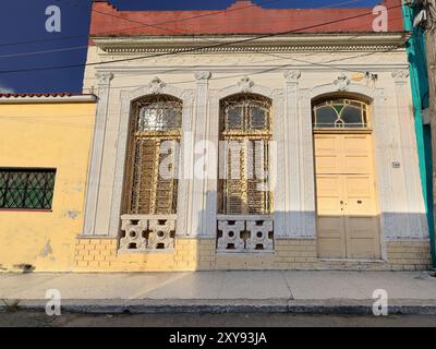 641 einstöckiges eklektisches Haus mit cremefarbenen Fassaden, Senftüren und Fensterläden, Grillfenstern, in der Calle Marti Straße in der Gemeinde Regla. Havanna-Kuba. Stockfoto