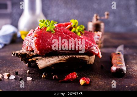 Rohes Fleisch mit Kräutern und Knoblauch, Marmorfleisch. Hölzerner Hintergrund. Stockfoto