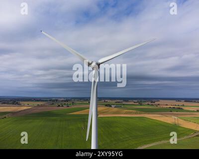 Vorderansicht einer Windkraftanlage aus der Luft. Schweden, Sommer, grüne und gelbe Felder und Ackerland. Bewölkt mit Sonnenstrahlen Stockfoto