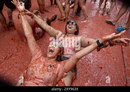 Valencia, Spanien. August 2024. Die Teilnehmer werden während des Tomatina-Festivals mit zerstoßenen Tomaten bedeckt. Wieder einmal fand das beliebte Festival La Tomatina in der valencianischen Stadt Buñol statt. Sechs Lkw mit 120.000 kg Tomaten wurden unter 22.000 Teilnehmern des Festivals geworfen. Quelle: SOPA Images Limited/Alamy Live News Stockfoto