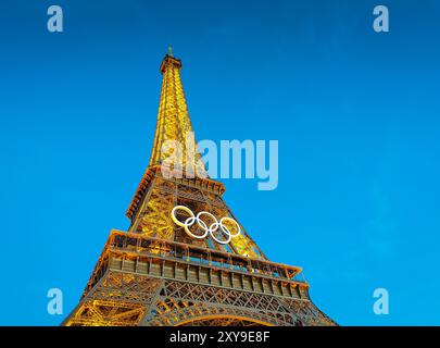08 28 2024 - Paris, Frankreich. Eiffelturm bei Nacht. Beleuchteter Turm mit olympischen Ringen am Abend Stockfoto