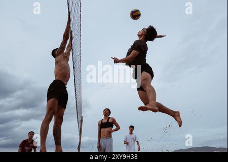 Asiatische vietnamesische Spieler spielen im Sommer Beachvolleyball an einem Sandstrand am Meer. Nha Trang, Vietnam - 21. Juli 2024 Stockfoto