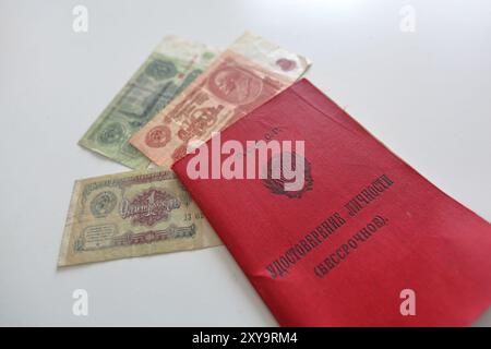 Ein rotes Heft mit der Aufschrift Russische Föderative Sozialistische Republik, Identitätsnachweis und sowjetische Rechnungen, die auf einer weißen Oberfläche ruhen. Stockfoto