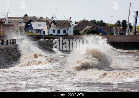 Stürmische Meere, die riesige Wellen gegen die Stufen am Eingang zum Hafen von Maryport erzeugen Stockfoto