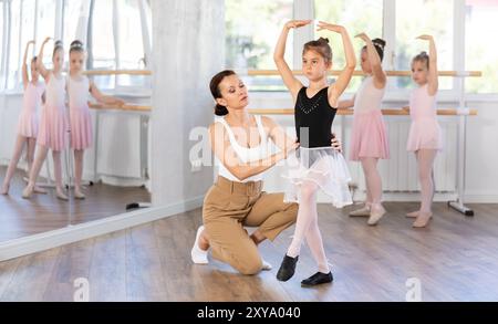 Im Studio korrigiert der Mentor Arm und Bein der Mädchen, unterrichtet die korrekte Dynamik und Ausführung von Bewegungen Stockfoto