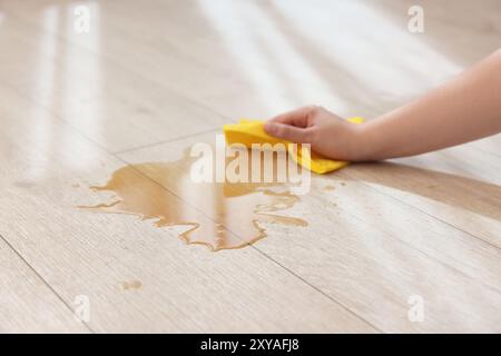 Frau wischt die Pfütze von verschüttetem Getränk auf dem Boden ab, Nahaufnahme Stockfoto