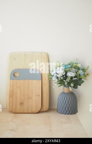 Schneidebrett aus Holz mit Kochutensilien und Blumenvase auf der Küchenzeile Stockfoto