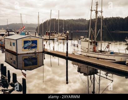 Der Yachthafen in Florence, Oregon am Siuslaw River, mit Fischerbooten und einer rustikalen Fischhütte, die sich im ruhigen Wasser spiegelt. Stockfoto