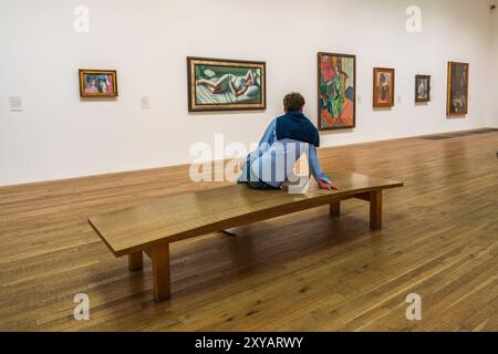 Tate Modern Art Museum Gallery Interior, ein Museum für zeitgenössische, moderne Kunst in London, Großbritannien. Sammlung von Gemälden mit einem Besucher, der auf einer Bank sitzt. Stockfoto