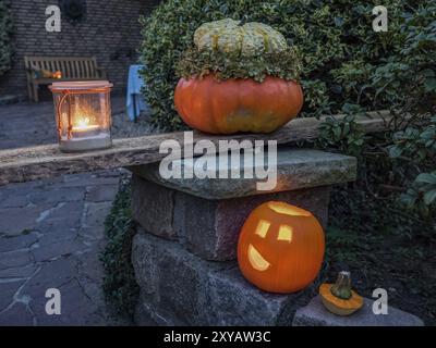 Beleuchtete Kürbisse und eine Kerze im Glas auf einer Steinwand, ein Thema der Halloween Dekoration im Garten bei Nacht, borken, münsterland, Deutschland, E Stockfoto