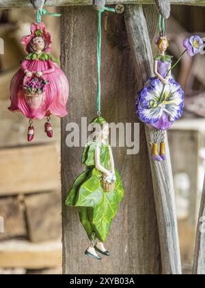 Drei farbenfrohe Figuren von Blumenmädchen, die an einem Holzbrett hängen, nostalgisch dargestellt, borken, münsterland, deutschland Stockfoto