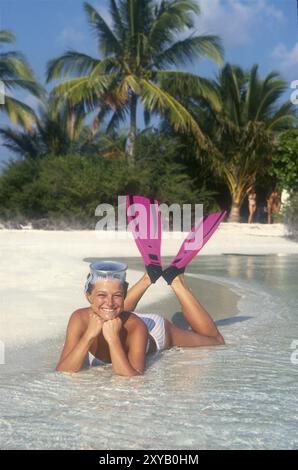 Fröhliche junge Frau im Bikini, die auf dem Bauch liegend mit gebeugten Beinen Schnorchelflossen Flossen und Tauchbrille Tauchen Tauchen Tauchen Brille ruhendes Kinn Stockfoto