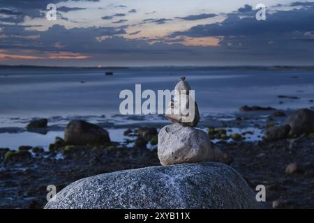 Steinpyramide an der Ostsee mit Blick auf das Meer bei Sonnenuntergang und Blue Hour. Steine als Silhouette. Spirituelle Sichtweise. Landschaftsaufnahmen von Poel Island Stockfoto