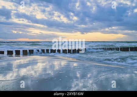 Sonnenuntergang am Strand der Ostsee. Reflexion am Strand. Stachelroynes reichen ins Meer. Blaue Stunde mit Wolken am Himmel. Landschaftsfoto in Zings Stockfoto