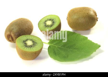 Halbierte Kiwis mit ganzen Kiwis und Blatt auf weißem Hintergrund Stockfoto