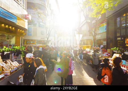 Seoul, Südkorea, 17. April 2015: Die Sonne beleuchtet Touristen, die die geschäftige Myeongdong Fußgängerzone entlang laufen, mit kommerziellem Handel von Geschäften, Schild Stockfoto