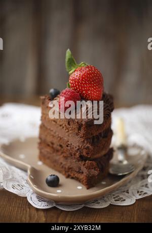 Stück Schokolade Kuchen mit Zuckerguss und frischen Beeren auf hölzernen Hintergrund Stockfoto